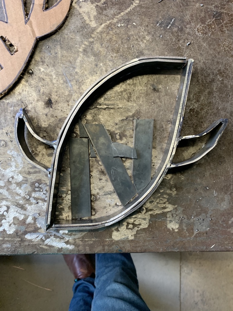 Welded football frame with side accents and N pieces on a workshop table